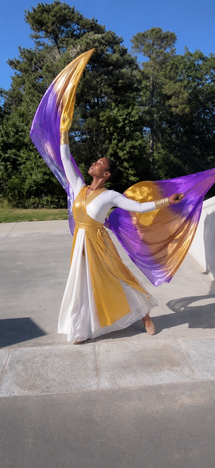 Worship dancer with flowing purple and gold flags